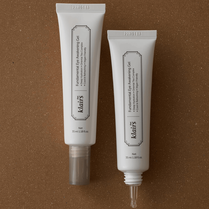 Produktbillede, der viser Klairs Fundamental Eye Awakening Gel i to udgaver – en lukket tube og en åben tube, der fremhæver den smalle applikatorspids. Emballagen har et minimalistisk hvidt design og fremhæver produktets fokus på fugt, kølende følelse og opfriskende pleje af øjenområdet.