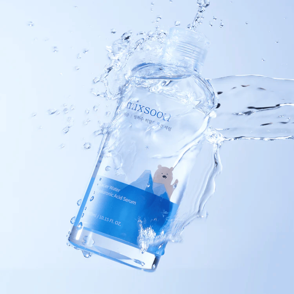 Mixsoon Glacier Water Hyaluronic Acid Serum-flaske med blå etiket og isbjørnsmotiv omgivet af sprøjtende vand mod lyseblå baggrund.