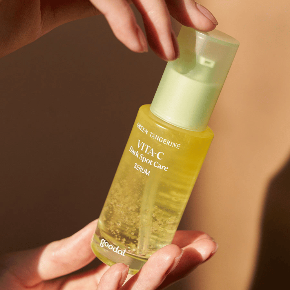 En person, der holder en flaske Green Tangerine Vita C Dark Spot Care Serum 40ml fra Goodal til hyperpigmentering og pleje af mørke pletter.