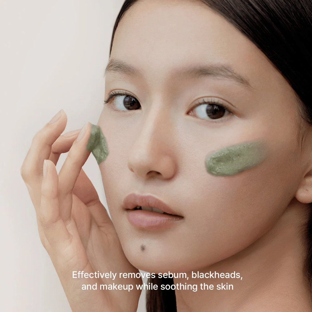 Model påfører den grønne cleanser på kinderne med fokus på at fjerne talg, hudorme og makeup, samtidig med at huden beroliges og føles balanceret.