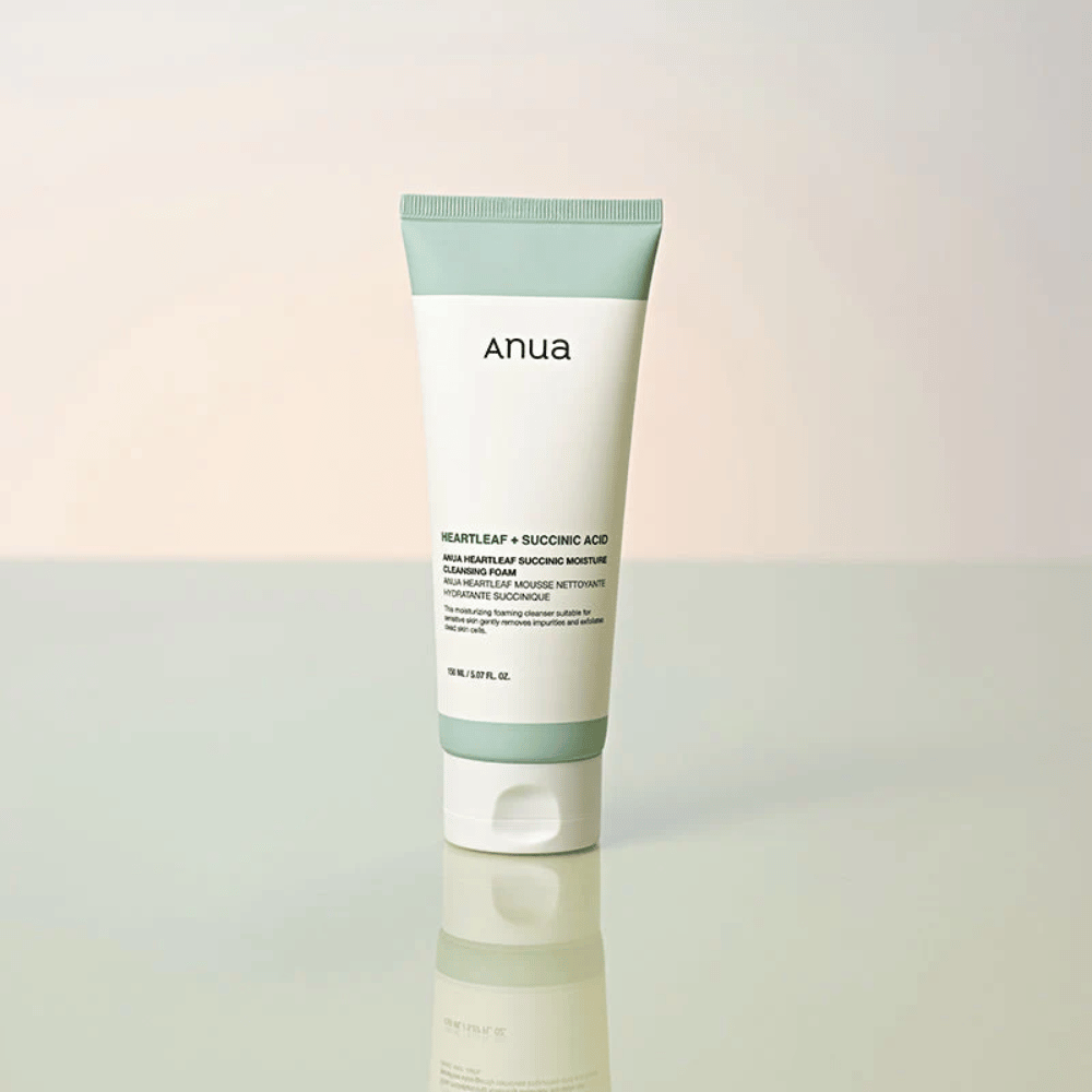 Fritstående produktbillede af Anua Heartleaf + Succinic Acid Moisture Cleansing Foam. Produktet vises stående på en reflekterende overflade, som tydeligt fremhæver emballagens design og brandets stilrene æstetik.