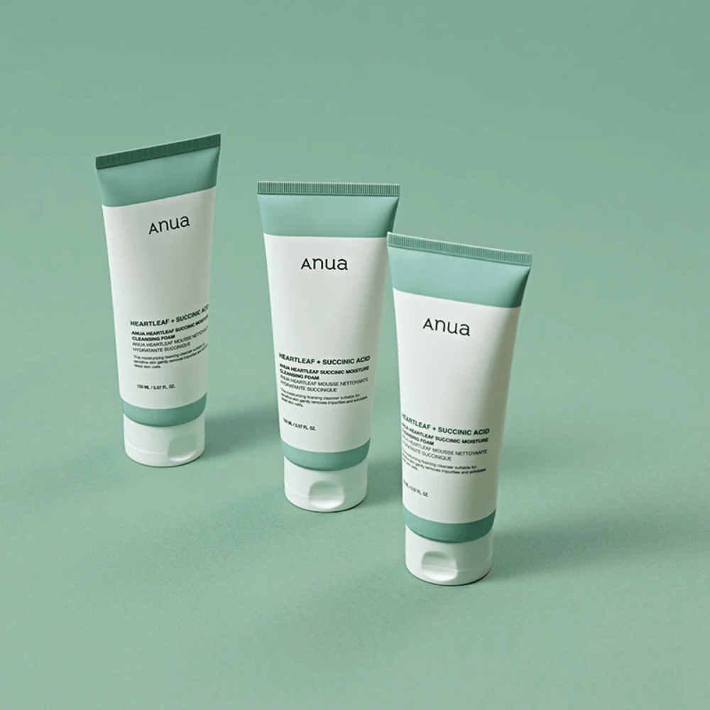 Tre pakninger af Anua Heartleaf + Succinic Acid Moisture Cleansing Foam præsenteret mod en lysegrøn baggrund. Billedet fremhæver produktets rene og minimalistiske design samt giver et professionelt indtryk af produktserien.