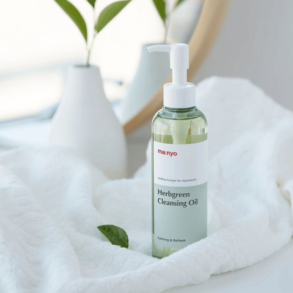 ma:nyo Herbgreen Cleansing Oil i pumpeflaske placeret på hvidt håndklæde, beroligende rensende olie med urtebaserede ingredienser til skånsom ansigtsrensning
