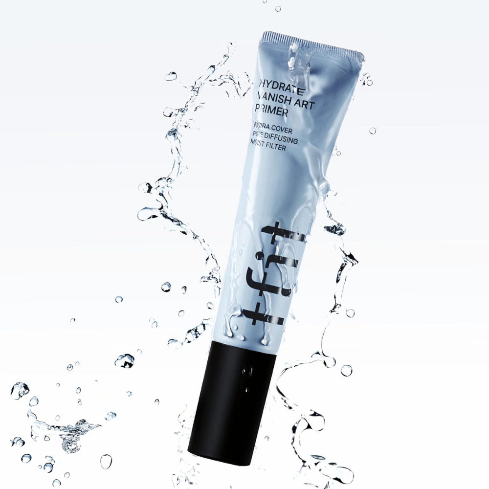 TFIT Hydrate Vanish Art Primer i blå tube omgives af sprøjtende vand, hvilket symboliserer produktets fugtgivende egenskaber og friske følelse ved påføring.