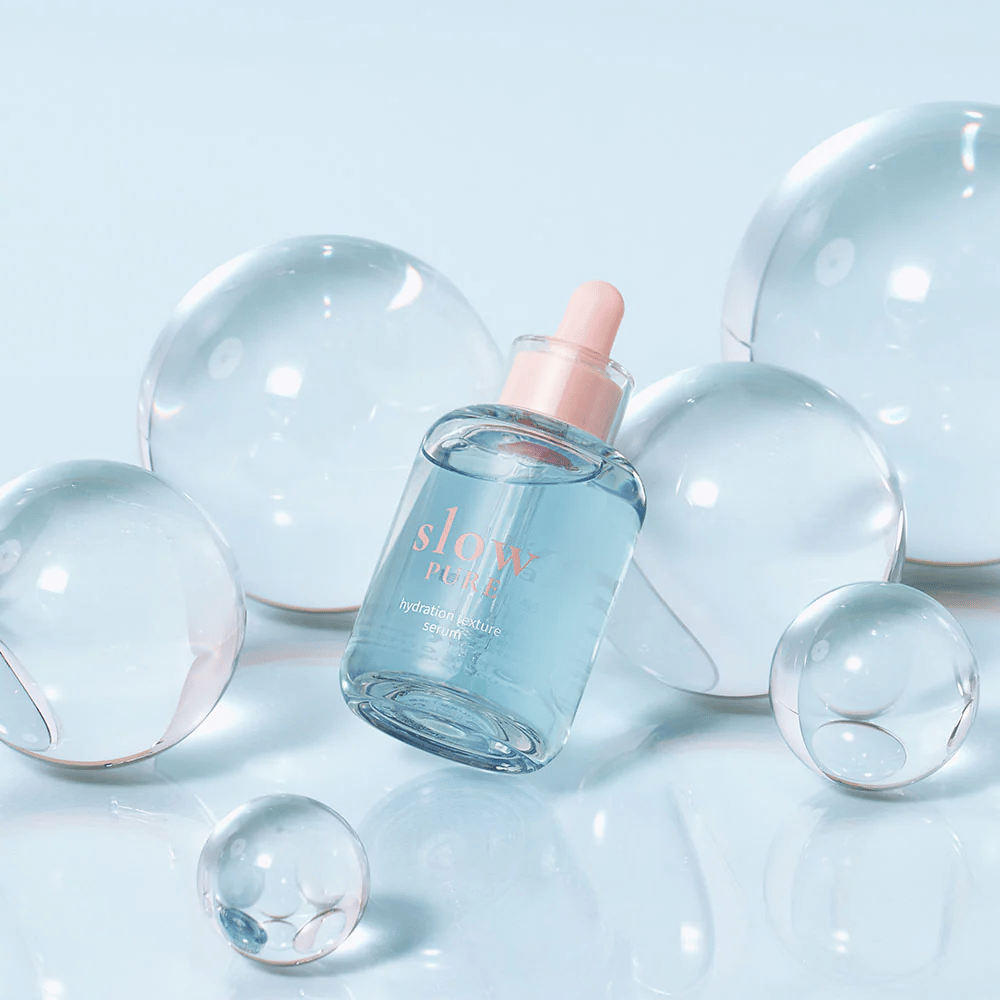 Slow Pure Hydration Texture Serum placeret blandt gennemsigtige bobler, symbol for intensiv fugtighed.