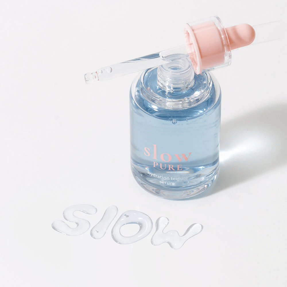 Slow Pure Hydration Texture Serum med åben pipette, tekst skrevet i serum på overfladen: "Slow".