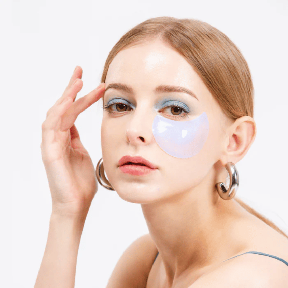 Model bærer en blåskinnende hydrogel eye patch under øjet for opfriskende effekt.