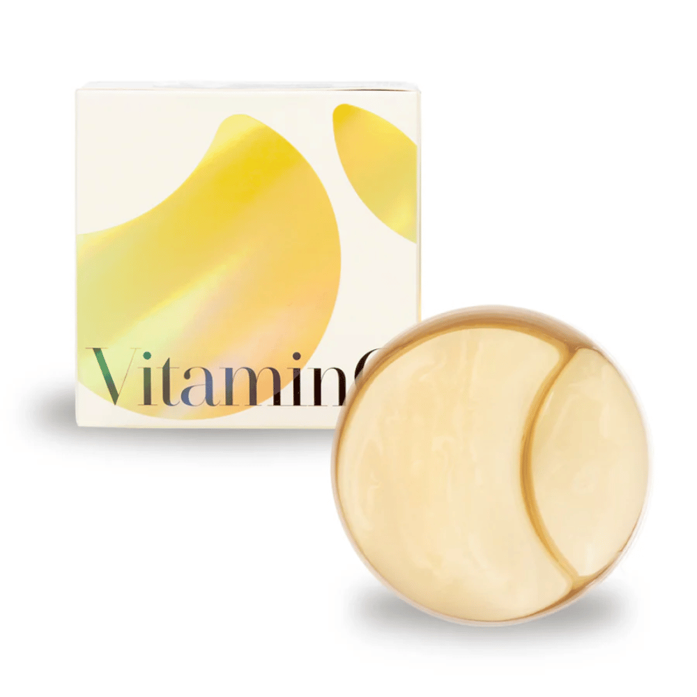 K-Secret Extra Illuminating Eye Gel Patches med vitamin C i guldfarvet hydrogel, krukke og pakke i baggrunden.
