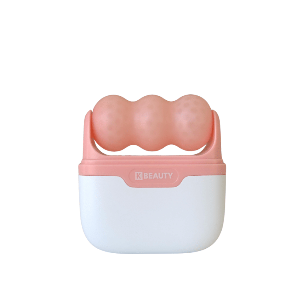 Billedet viser en K-Beauty Ice Roller med et hvidt og lyserødt håndtag. Produktet har tre afrundede, prikkede ruller i lyserød farve på toppen, designet til at køle og massere ansigtet. Baggrunden er helt hvid.