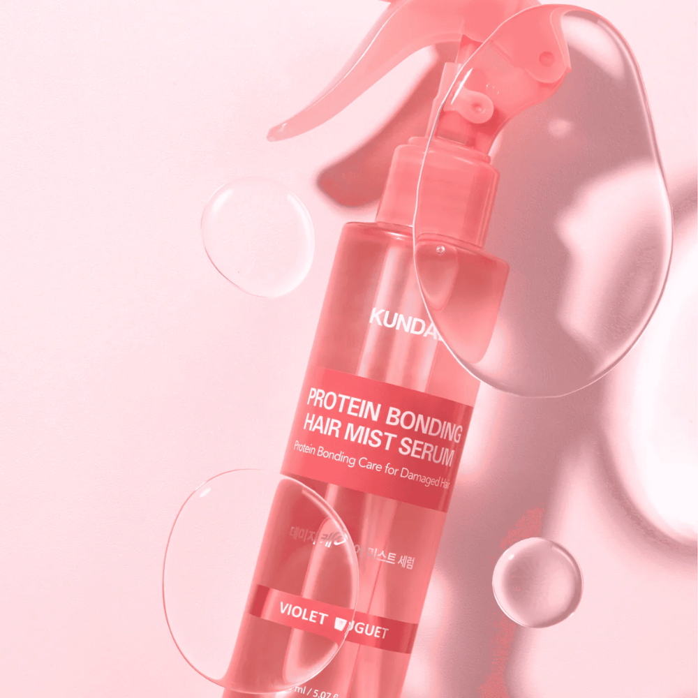 KUNDAL Protein Bonding Hair Mist Serum Violet Bouquet i lyserød sprayflaske, fotograferet mod lyserød baggrund med vanddråber.