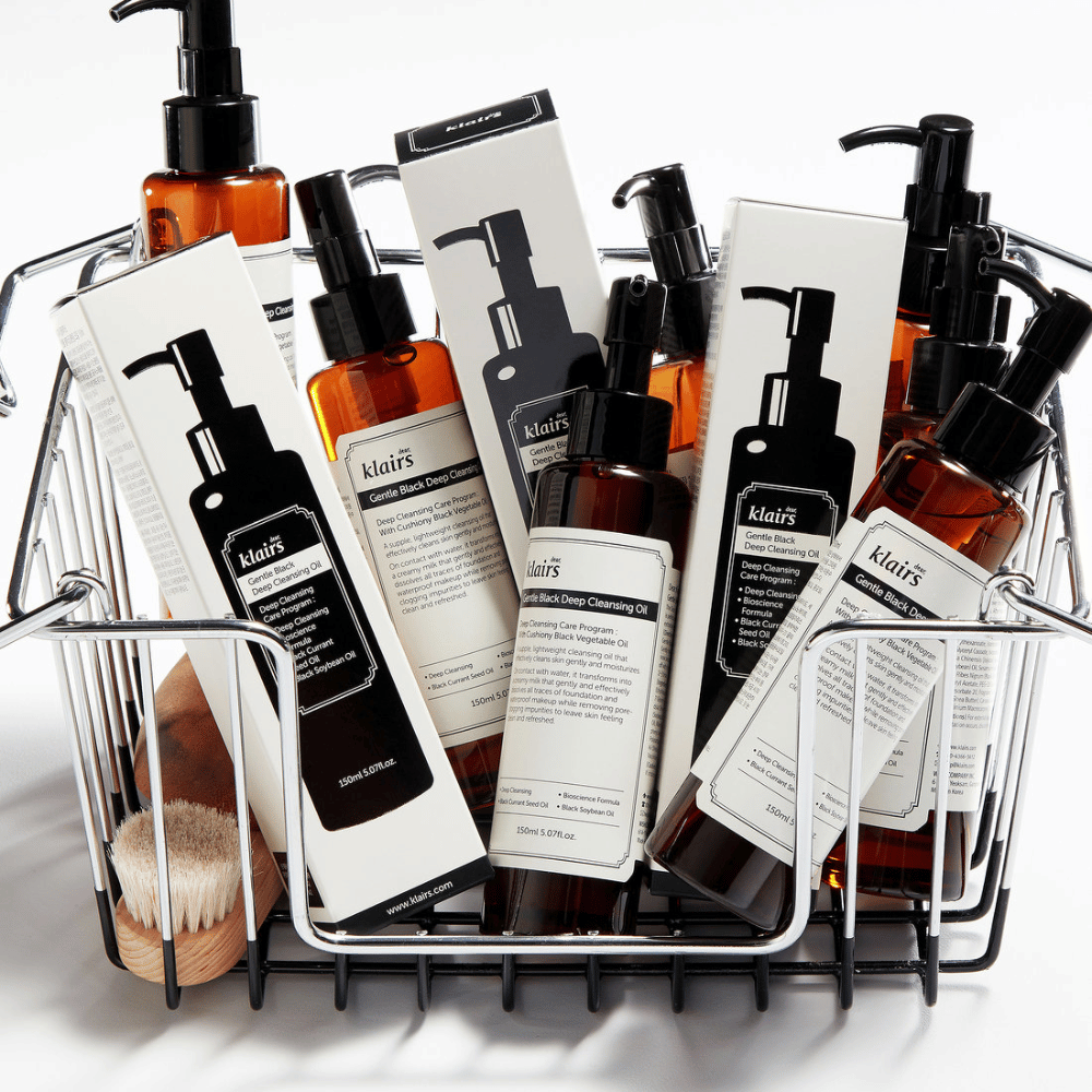 En minivogn fyldt med hudplejeprodukter fra Klairs, inklusive Gentle Black Deep Cleansing Oil i gennemsigtige flasker med sorte pumper og matchende emballager.