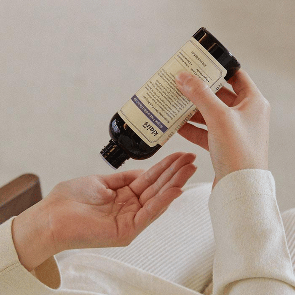 En person holder en flaske af Klairs Supple Preparation Facial Toner op og ned over sin hånd, klar til at dosere produktet.