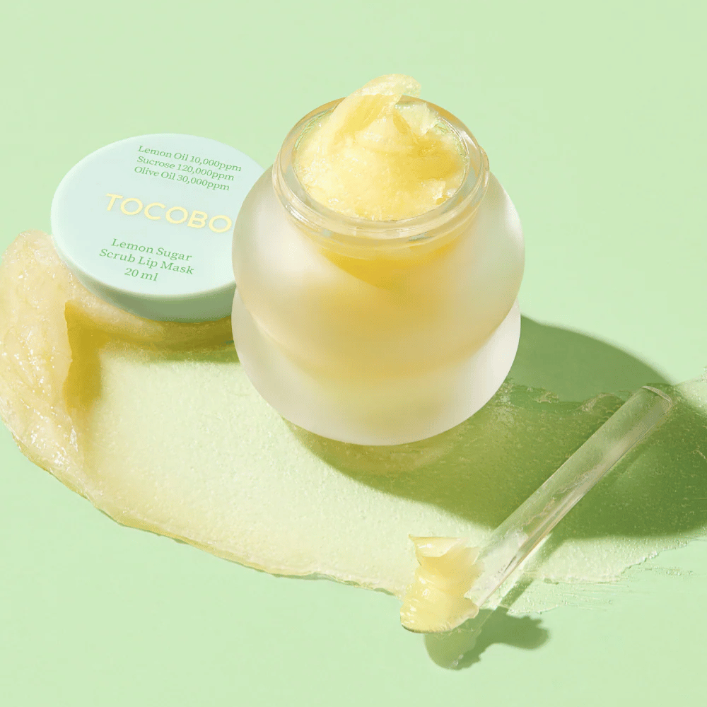 Åben krukke med Tocobo Lemon Sugar Scrub Lip Mask på en grøn baggrund, med indholdet tydeligt synligt.