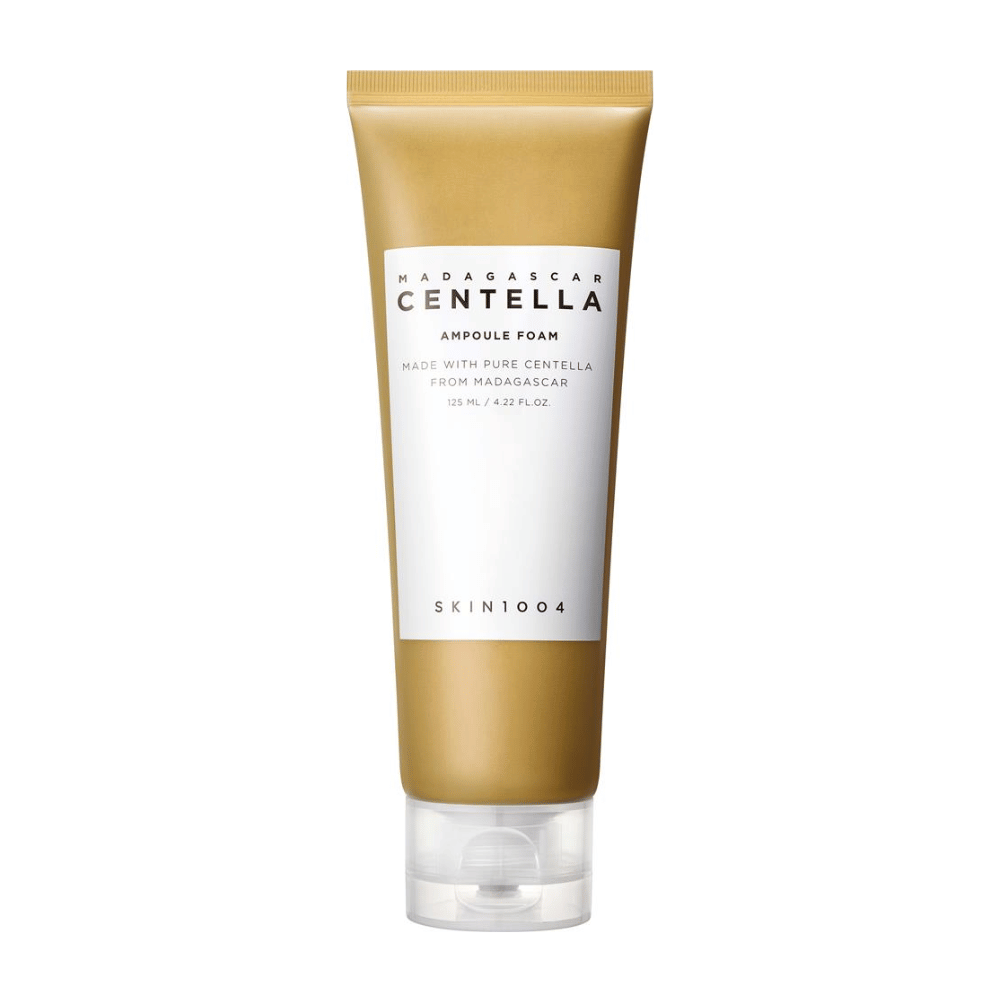Billedet viser et rør af "Madagascar Centella Ampoule Foam" fra mærket SKIN1004. Det er et rengøringsprodukt til ansigtet, som indeholder 125 ml / 4.22 fl.oz. Formlen er baseret på ren Centella, udvundet fra planter i Madagaskar. Produktet er designet til skånsomt at rense og pleje huden.