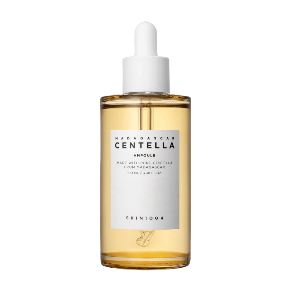 Billedet viser en flaske med "Madagascar Centella Asiatica 100 Ampoule" fra SKIN1004. Flasken indeholder 100 ml og påstår at være lavet med ren Centella fra Madagaskar. Produktet ser ud til at være et hudplejeserum, og den enkle etiket giver et indtryk af renhed og naturlighed. Flasken med dråbekork antyder, at dette er et nøje doseret hudplejeprodukt.
