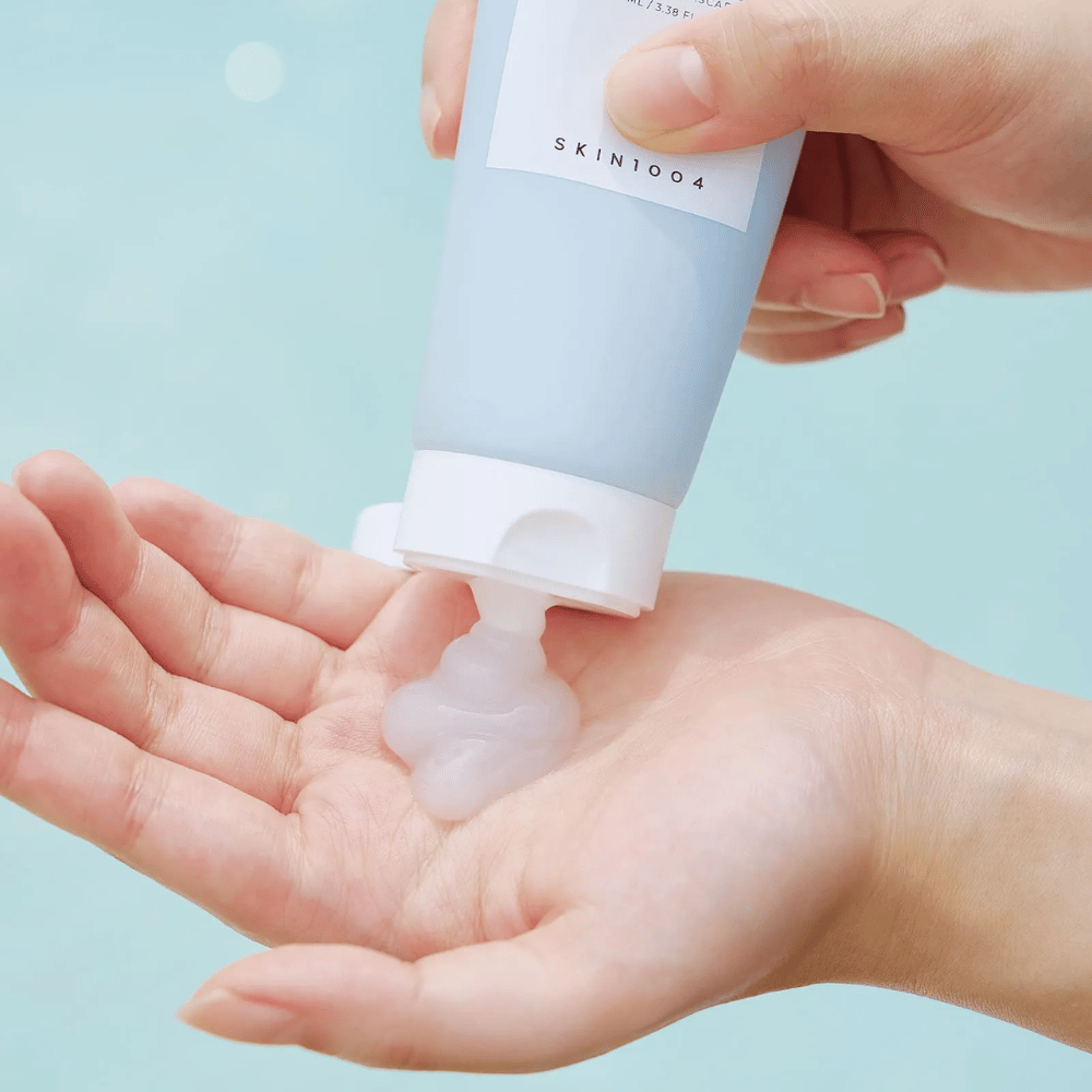 Billedet viser nogen, der presser en klar geléagtig substans ud fra en tube mærket "SKIN1004 Madagascar Centella Hyalu-Cica Sleeping Pack" som indeholder 100 ml produkt.