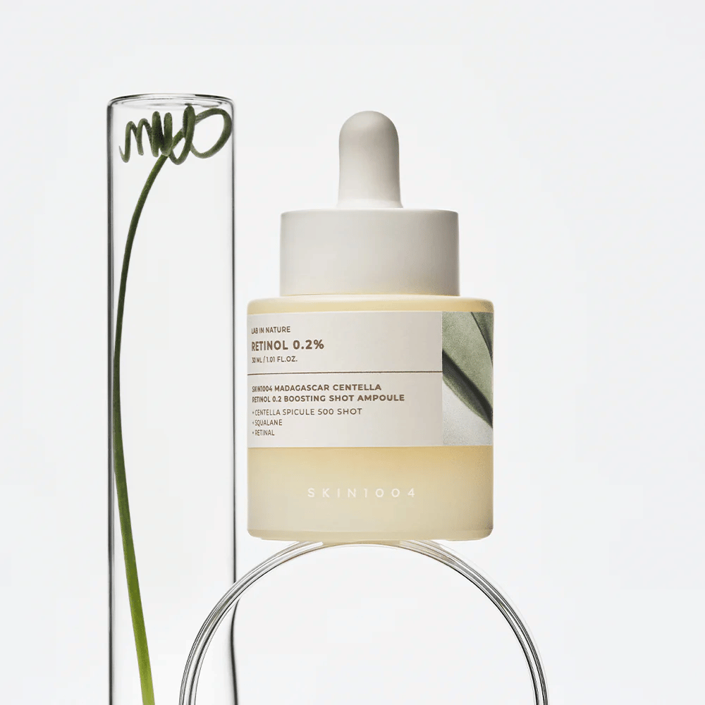 SKIN1004 Madagascar Centella Retinol 0.2 Boosting Shot Ampoule i livsstilsbillede med botaniske elementer – ansigtsserum der støtter hudens fornyelse og styrker hudbarrieren.