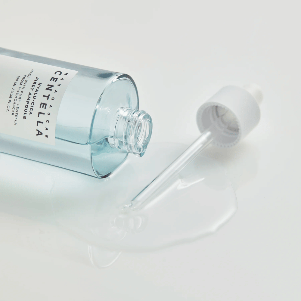 Nærbillede af åben flaske Skin1004 Madagascar Centella Hyalu-Cica First Ampoule med pipette liggende og serum spredt på hvid overflade.