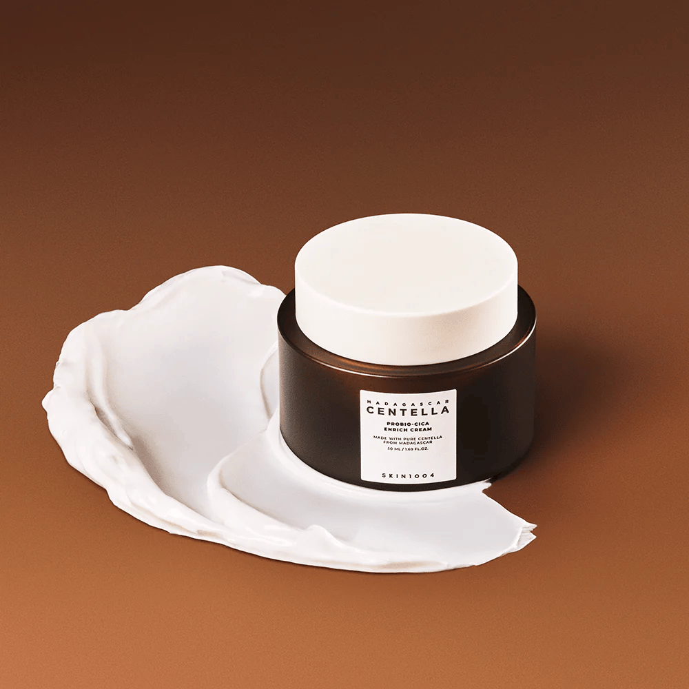 SKIN1004 Madagascar Centella Probio-Cica Enrich Cream placeret på et lag creme – fugtgivende og beroligende ansigtscreme med centella asiatica.