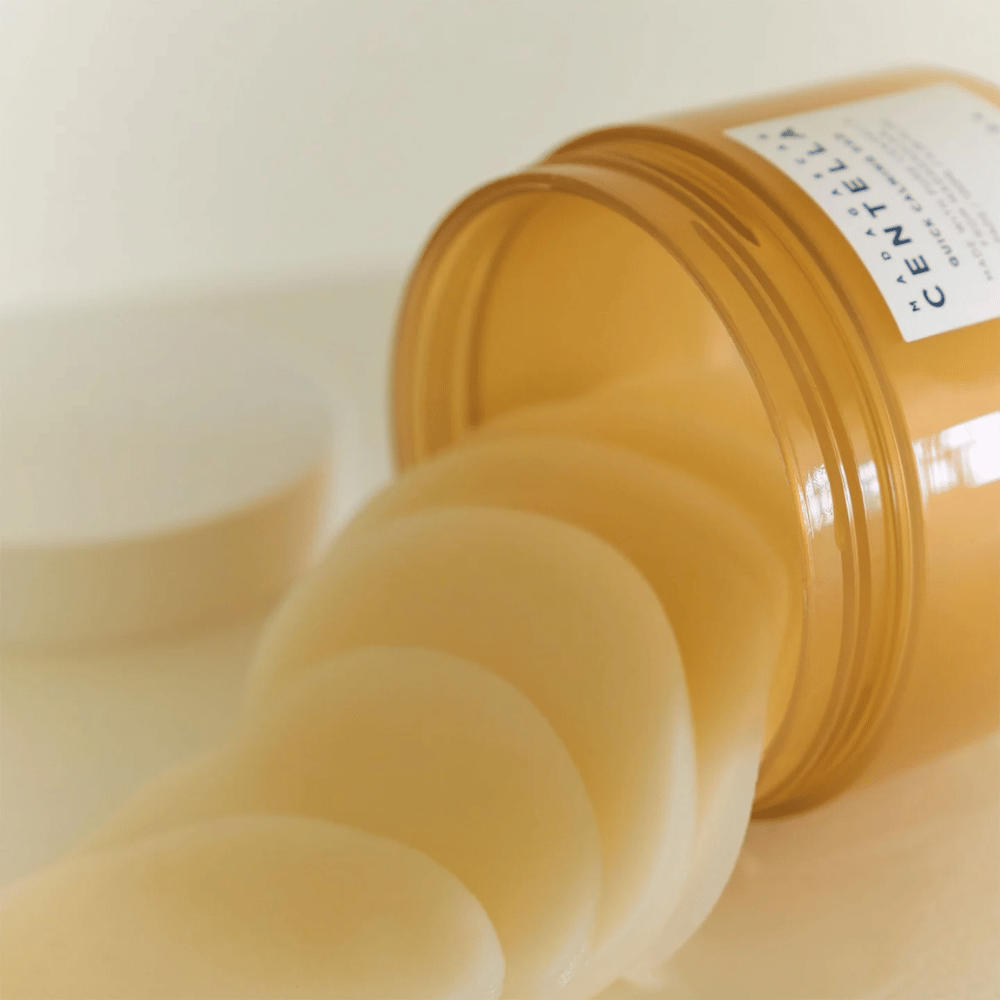 Åbnet bøtte med SKIN1004 Madagascar Centella Quick Calming Pad – flere runde toner pads i lysegul væske ses, bøtten er ravfarvet med hvid etiket.
