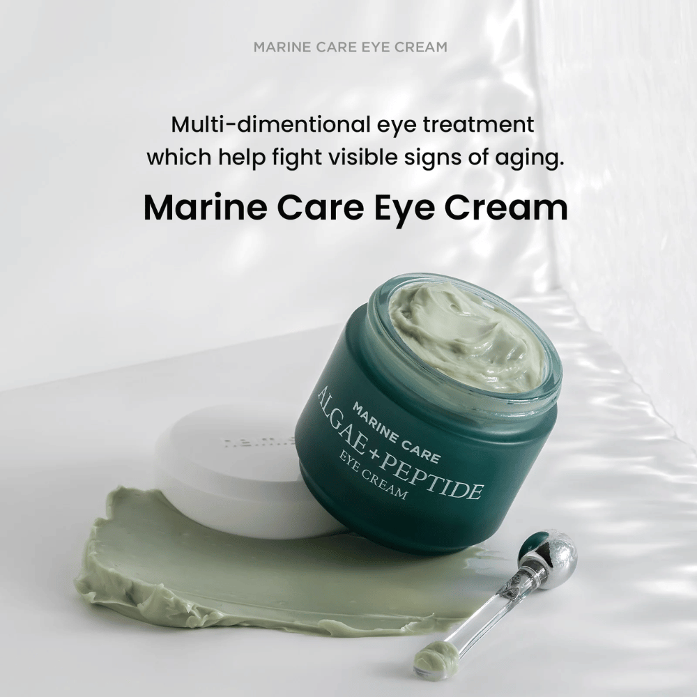 Heimish Marine Care Algae + Peptide Eye Cream i en åben dåse med grønlig creme. Cremen er spredt ved siden af dåsen, og en applikator ligger ved siden af. Produktet bekæmper alderstegn og giver intensiv fugt.