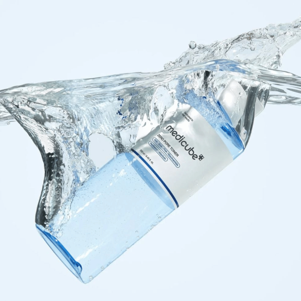 Medicube Zero Pore Toner 250 ml, eksfolierende toner med AHA, BHA og PHA. Gennemsigtig blå flaske omgivet af et stort vandsprøjt.
