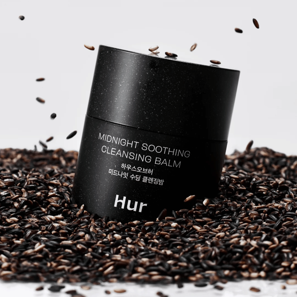 Hvordan Midnight Soothing Cleansing Balm i sort krukke placeret på sorte frø. Beroligende rensebalm, der opløser makeup og urenheder, samtidig med at huden plejes.