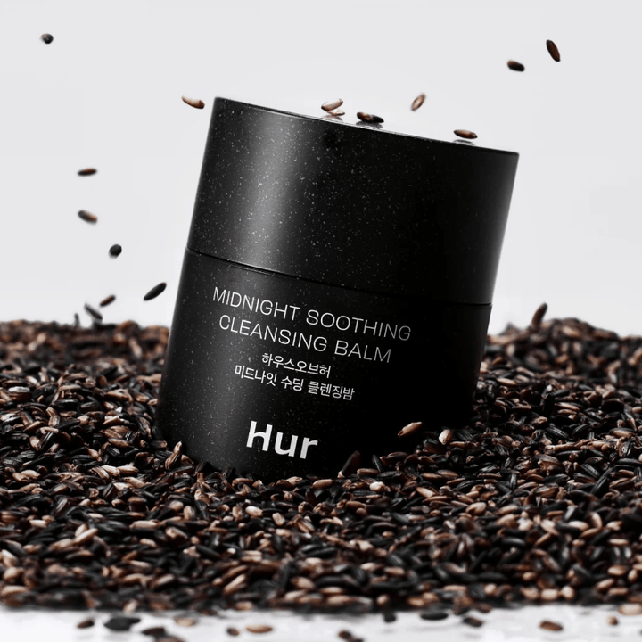 Hvordan Midnight Soothing Cleansing Balm i sort krukke placeret på sorte frø. Beroligende rensebalm, der opløser makeup og urenheder, samtidig med at huden plejes.