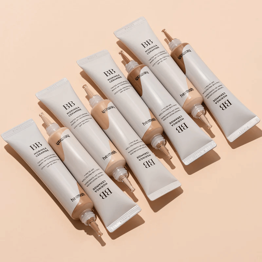 Flere tuber af Heimish Moringa Ceramide BB Cream arrangeret på lys beige baggrund. Billedet fremhæver de forskellige nuancer og produktets elegante, minimalistiske emballagedesign.