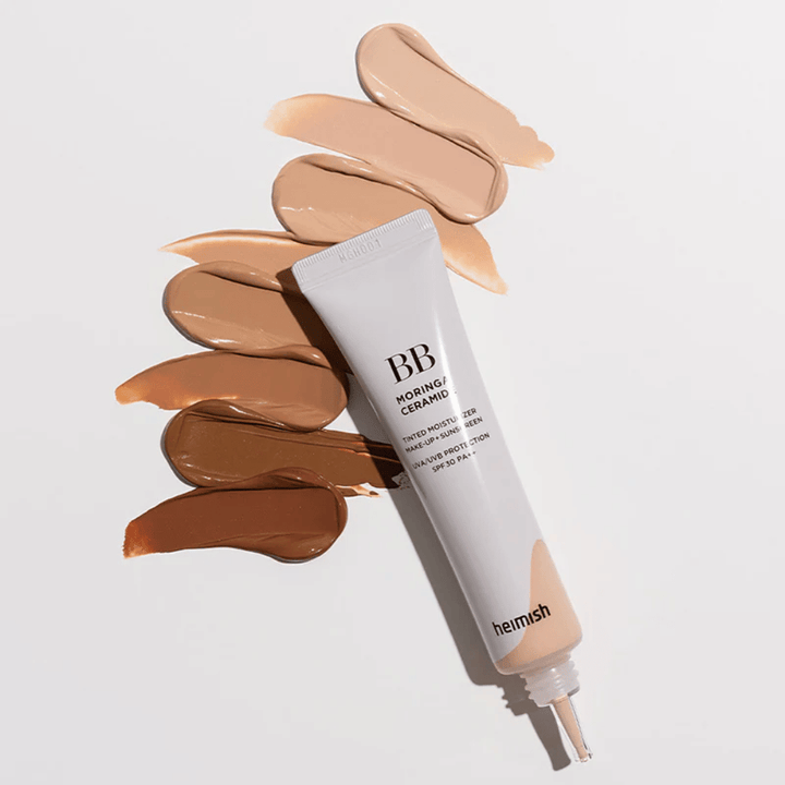 Heimish Moringa Ceramide BB Cream omgivet af flere nuanceprøver i forskellige hudtoner. Billedet viser produktets brede farveudvalg og den cremede konsistens, som giver naturlig dækning og en ensartet hudtone.