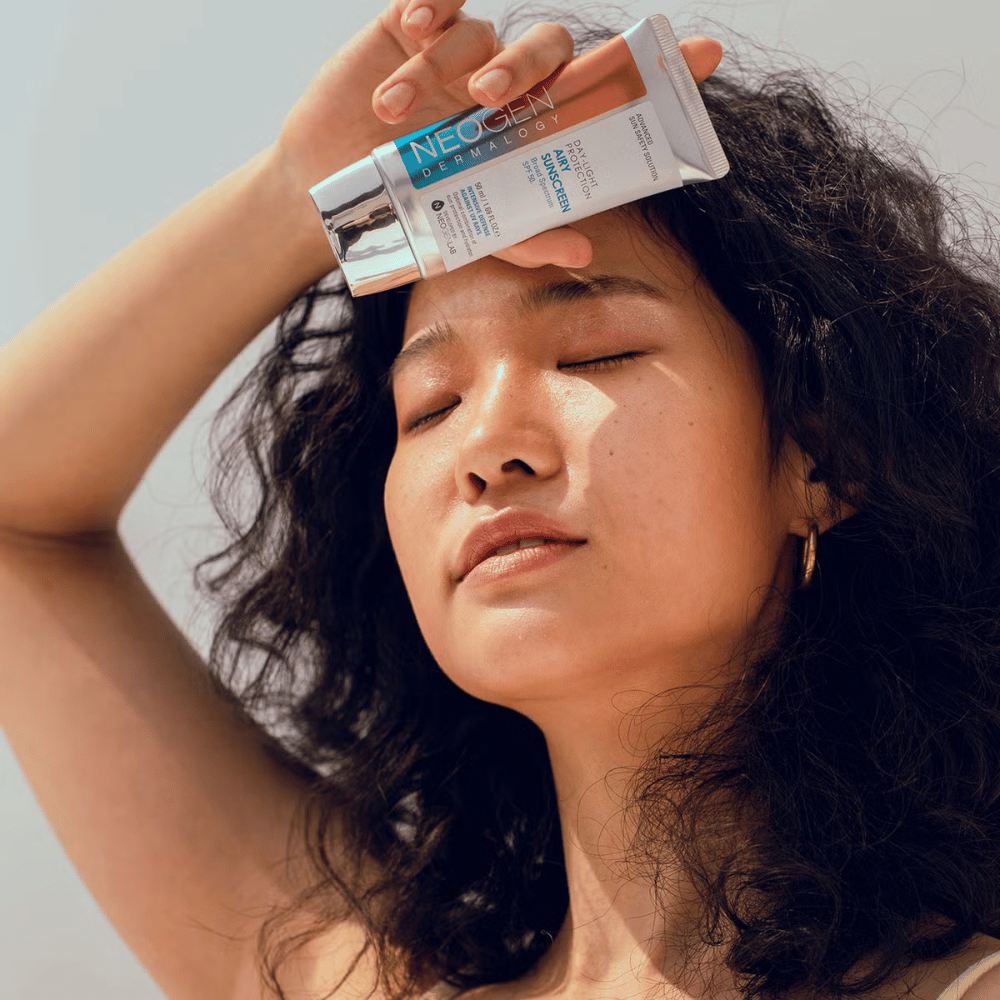 Neogen Dermalogy Day-Light Protection Airy Sunscreen SPF50 50ml – let solcreme med bredspektret UV-beskyttelse, vist i brug i sollys.