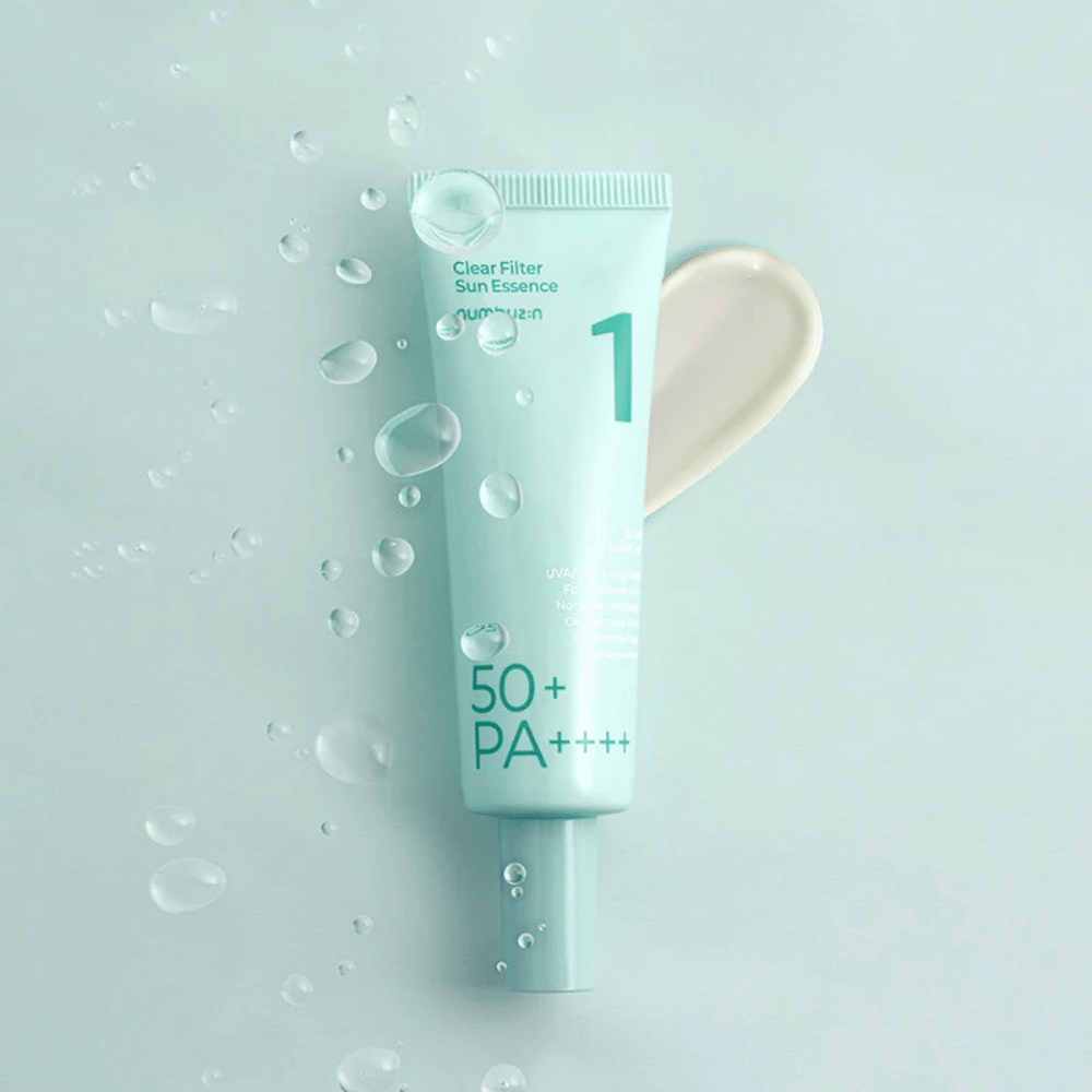 En lyseblå tube med No.1 Clear Filter Sun Essence SPF 50+ PA++++. Tuben er dekoreret med vanddråber, og en klat af produktet vises ved siden af. Produktet er designet til at give høj solbeskyttelsesfaktor og beskyttelse mod UVA/UVB-stråler.
