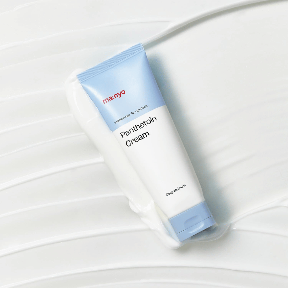 2. Ma:nyo Panthetoin Cream – fugtgivende ansigtscreme i hvid og lyseblå tube omgivet af cremet tekstur på hvid baggrund