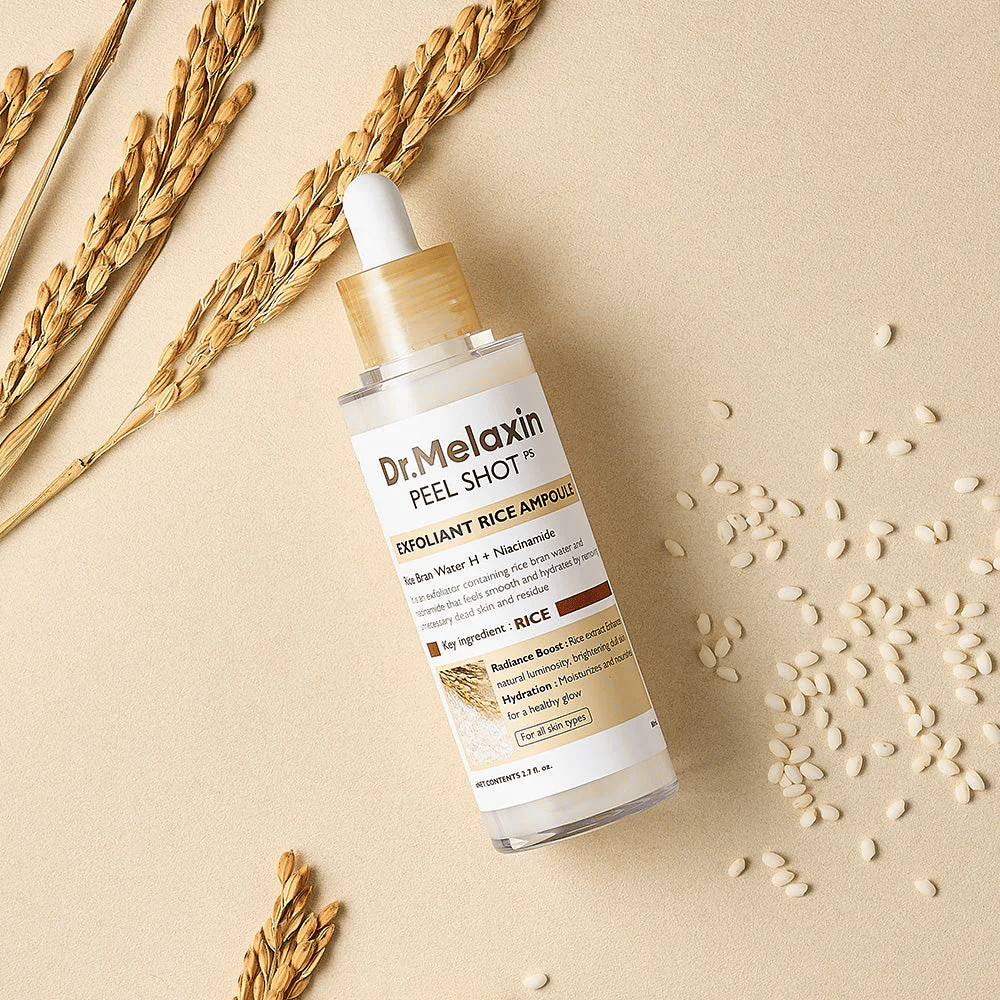 Dr.Melaxin Peel Shot Rice Ampoule liggende på sandfarvet overflade med ris og aks, eksfolierende ansigtsampul der kombinerer mild peeling med intens fugt.