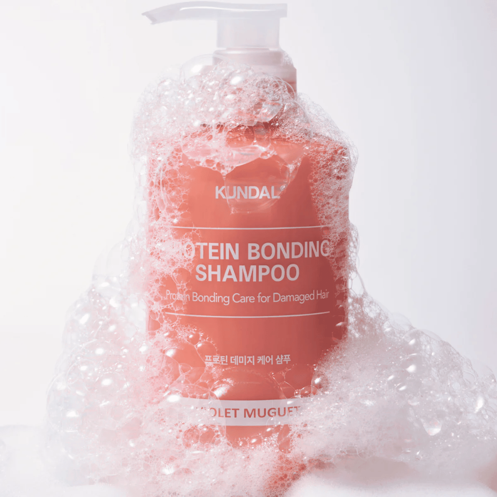 KUNDAL Protein Bonding Shampoo Violet Muguet dækket af rigeligt skum, reparerende shampoo til skadet hår.