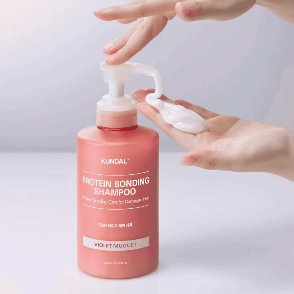 Hånd pumper ud KUNDAL Protein Bonding Shampoo Violet Muguet i cremet konsistens, reparerende shampoo til skadet hår.