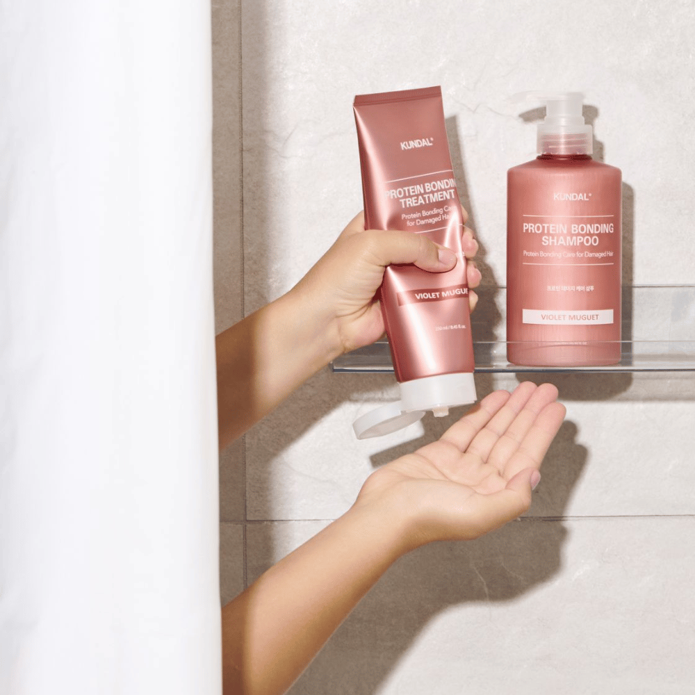 KUNDAL Protein Bonding Treatment Violet Muguet bruges i bruseren, med Protein Bonding Shampoo placeret på hylden ved siden af.