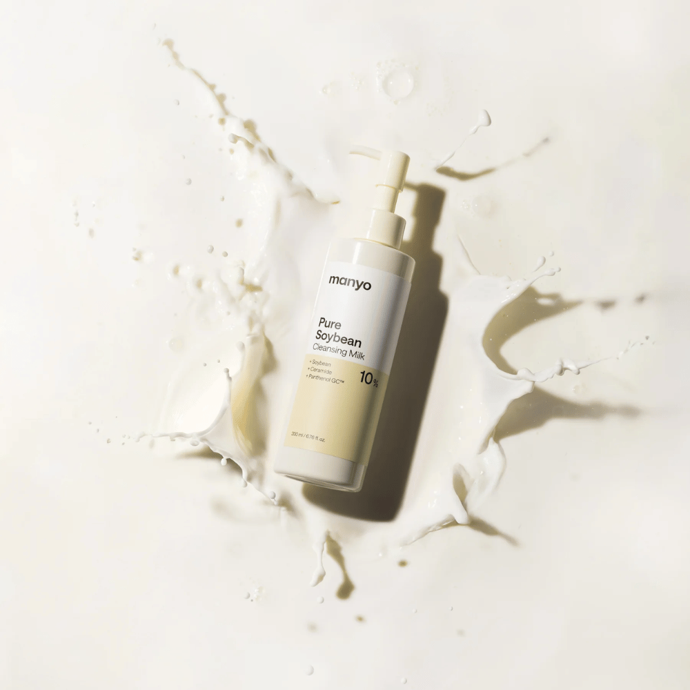 1. Ma:nyo Pure Soybean Cleansing Milk – mild rensemælk med soja i pumpeflaske omgivet af mælkestænk på lys baggrund