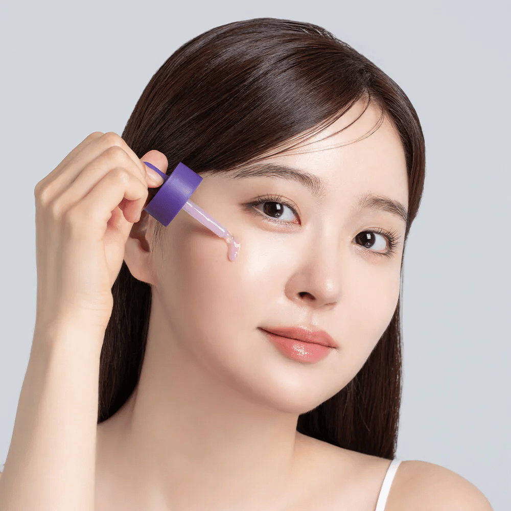 Påføring af Cellology Purple Carrot Pore Ampoule med pipette på ansigtet til porepleje og en mere ensartet hudtekstur.