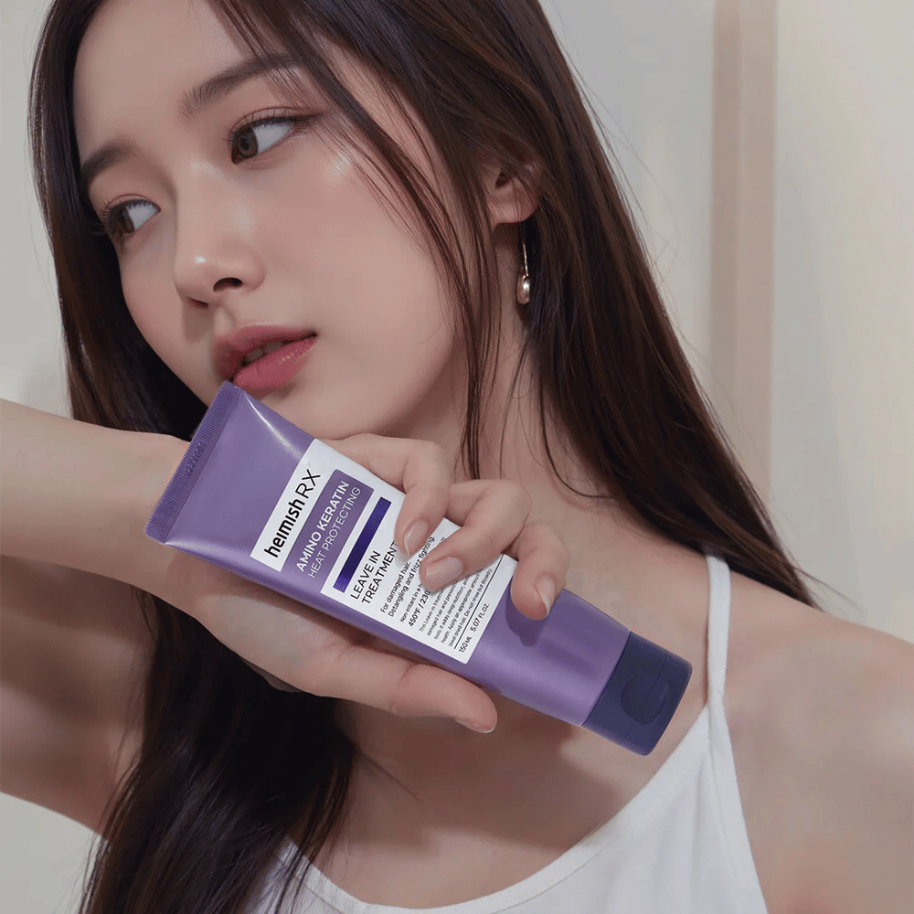 Kvinde med langt, skinnende hår holder i Heimish RX Amino Keratin Leave-In Treatment – viser produktet som et plejende og varmebeskyttende trin i hårplejerutinen.