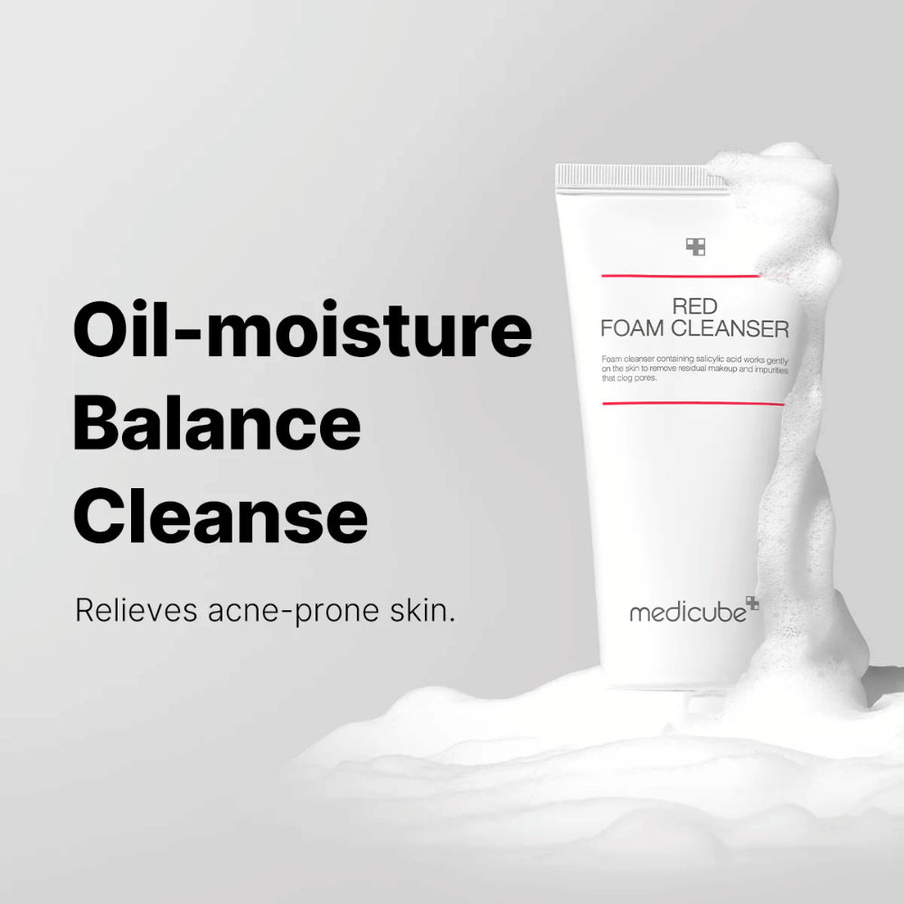 Tube med Medicube Red Foam Cleanser står oprejst blandt skummende skum. Teksten "Oil-moisture Balance Cleanse" vises til venstre, med beskrivelsen "Relieves acne-prone skin" nedenunder. Baggrunden er lysegrå.