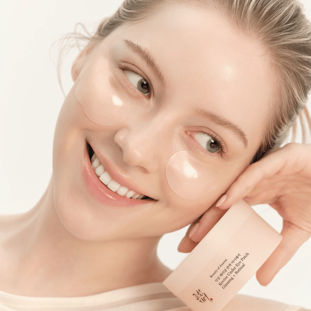 Model med Beauty of Joseon under eye patches og produkt i hånden, øjenpatches med ginseng og retinal for et mere vågent og glattere øjenområde.
