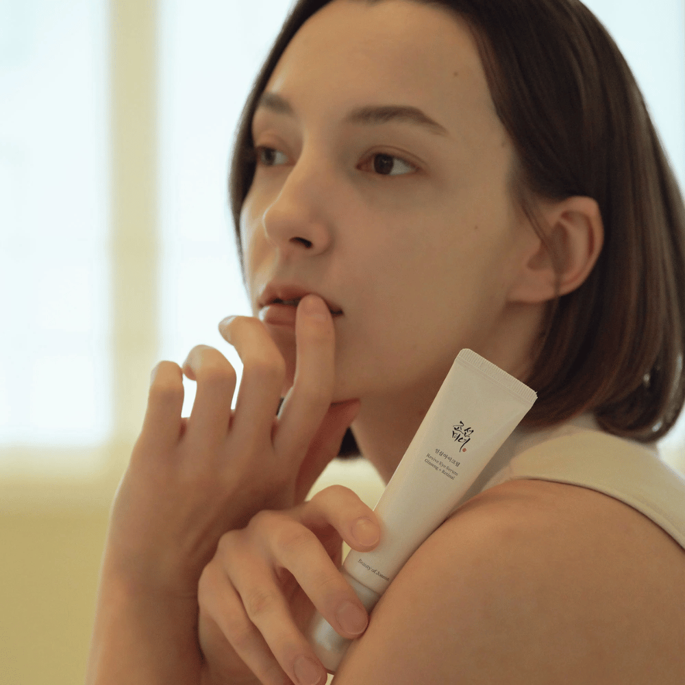 Model holder i Beauty of Joseon Revive Eye Serum og påfører forsigtigt på huden for en fugtet og glat øjenkontur.