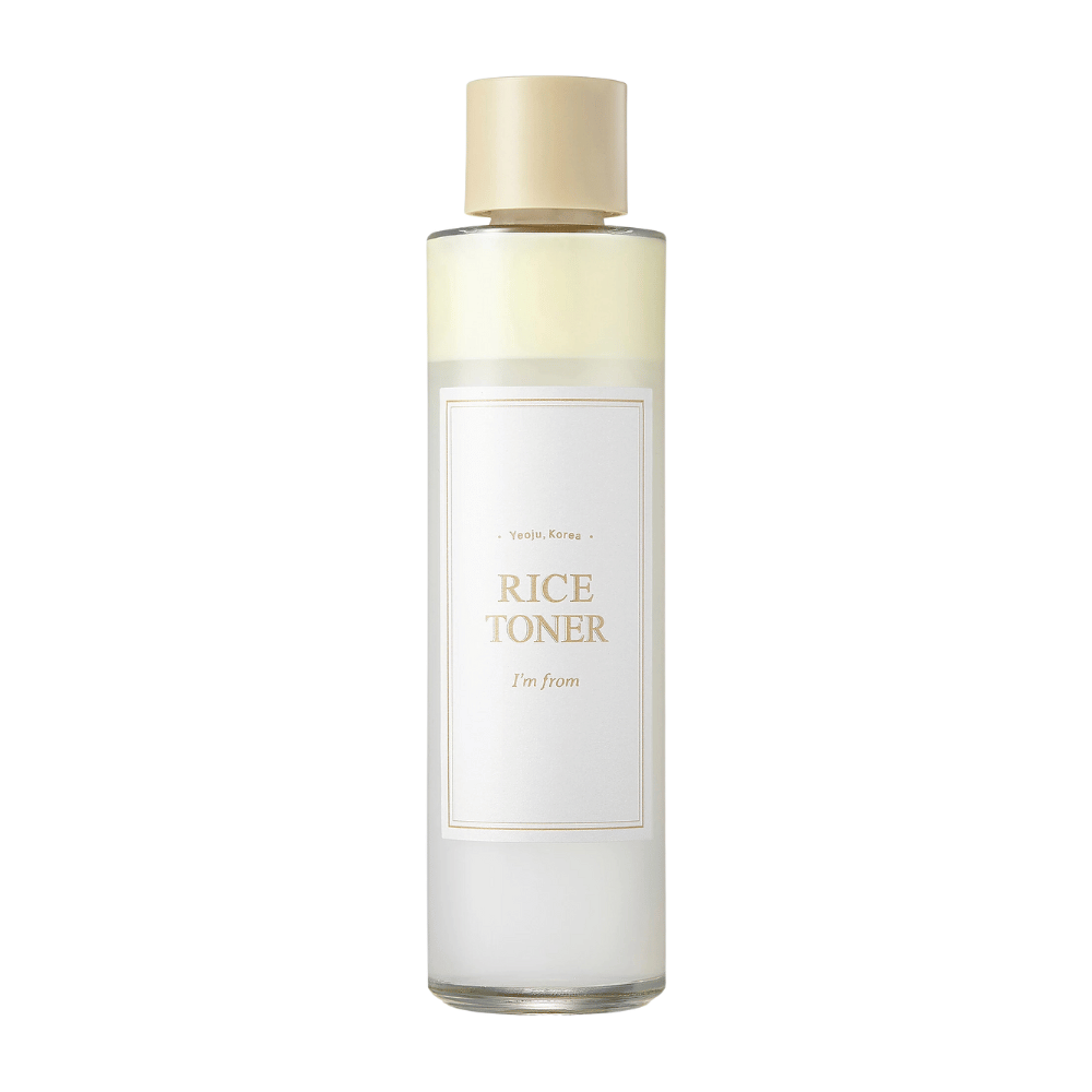 En transparent flaske med guld låg og etiket der angiver "Rice Toner I'm from Yeojü, Korea". Flasken indeholder en lys væske, sandsynligvis toner baseret på risekstrakt. Designet er rent og minimalistisk. Baggrunden er hvid.