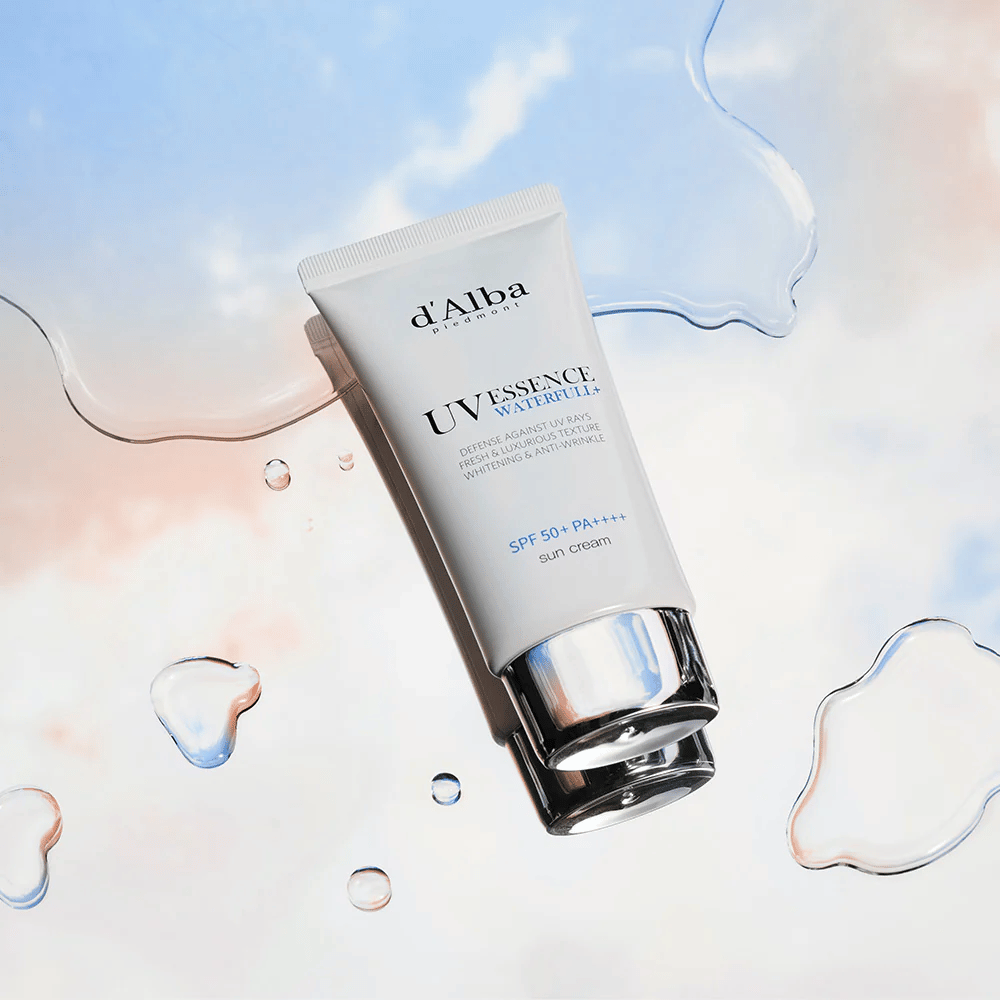 Produktbillede af d'Alba UV Essence Waterfull+ Sun Cream med SPF 50+ PA++++, placeret mod en baggrund med vandsprøjt og blårød himmel – symboliserer let og fugtgivende solbeskyttelse.