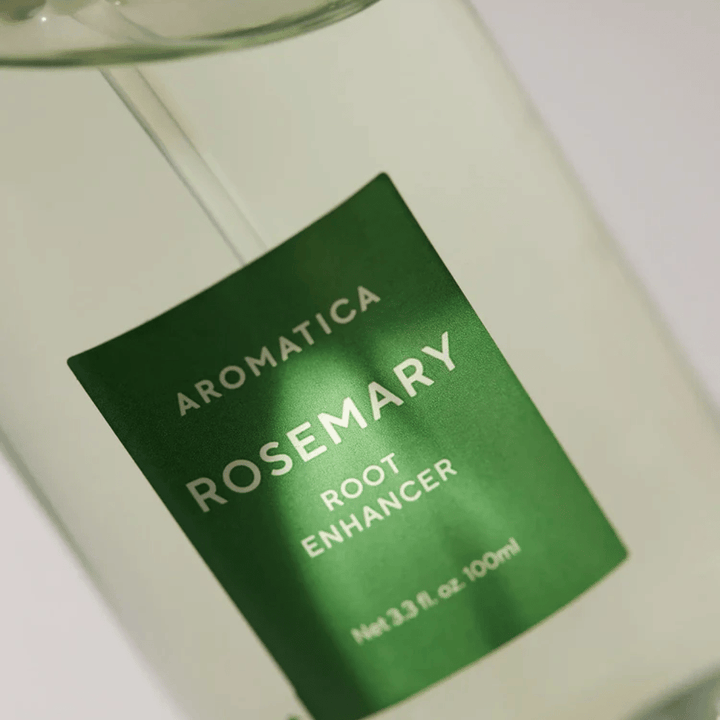 Detaljebillede af etiketten på AROMATICA Rosemary Root Enhancer. Den grønne etiket og den transparente flaske fremhæver produktets rene og minimalistiske udseende.