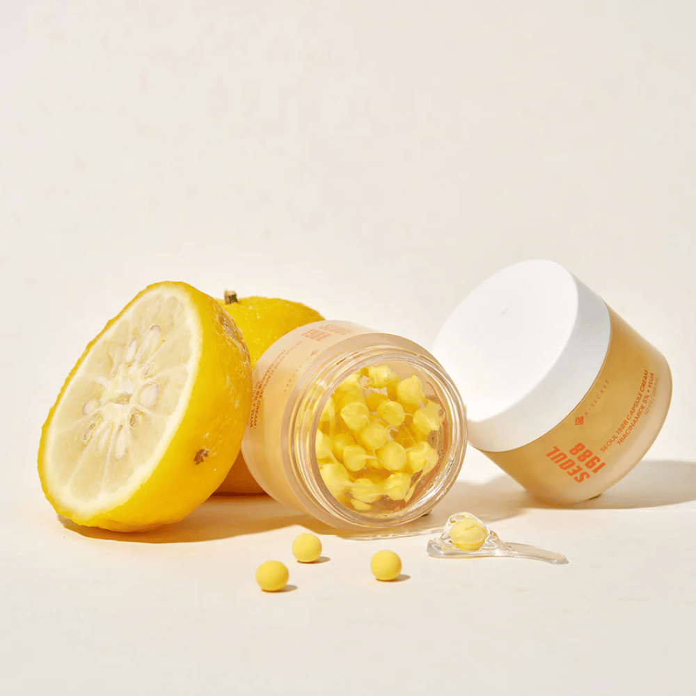 Åben krukke med gule kapsler ved siden af halveret yuja-frugt, der fremhæver C-vitaminrig formel.