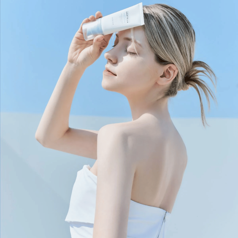 En kvinde anvender SKIN1004 Madagascar Centella Hyalu-Cica Water-Fit Sun Serum 50ml for at beskytte ansigtet mod UV-stråler.