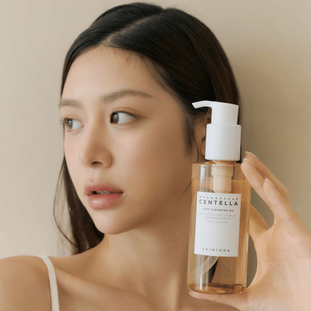 En kvinde som holder en flaske SKIN1004 Madagascar Centella Light Cleansing Oil 200 ml ansigtsrens.