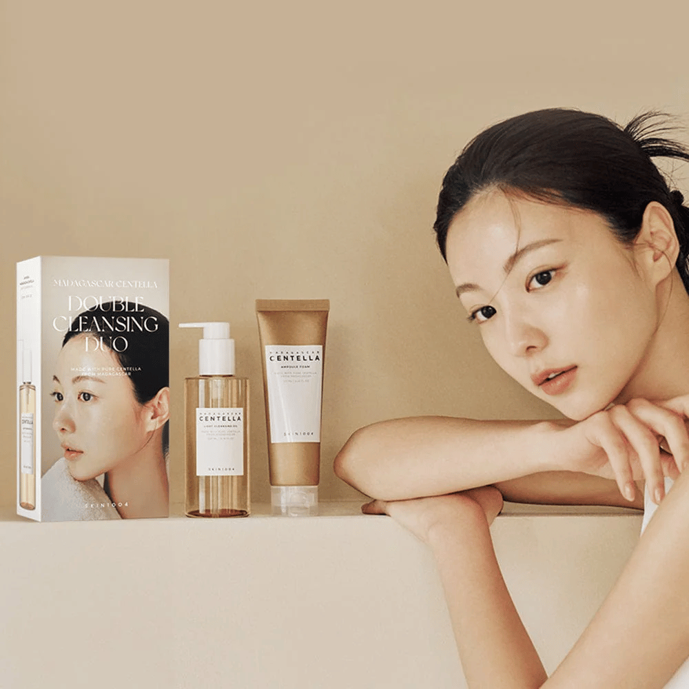 SKIN1004 Madagascar Centella Double Cleansing Duo Set med karton, oliebaseret rengøring, skumrengøring og model med fugtet hud mod beige baggrund.
